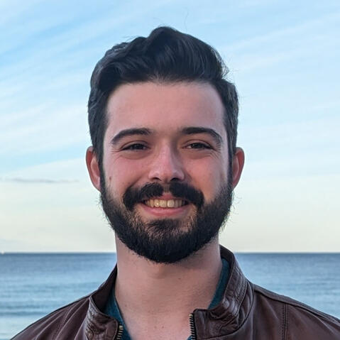 Professional headshot of Dashiell Sacks, smiling in front of the ocean.